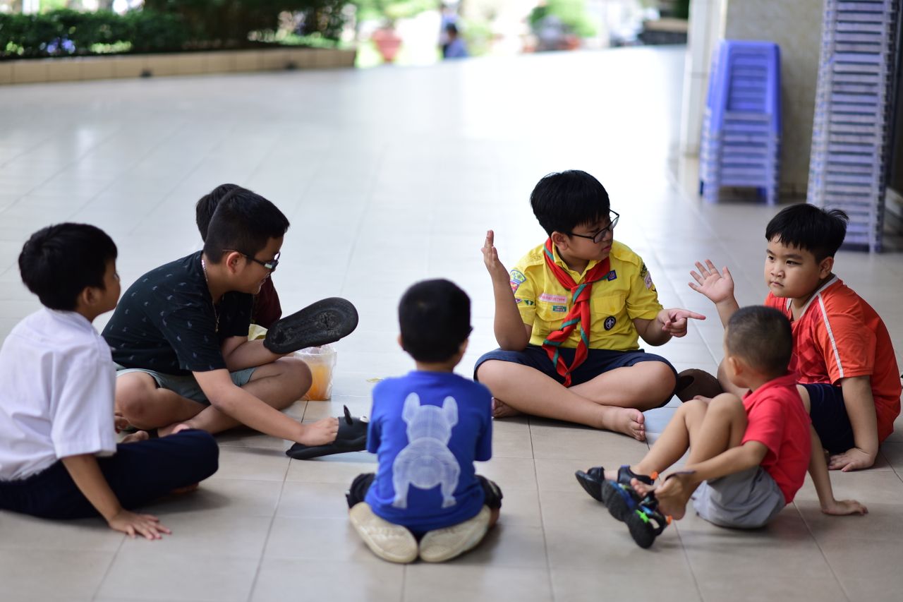 Children gathered in a discussion indoors, engaging and interacting together.